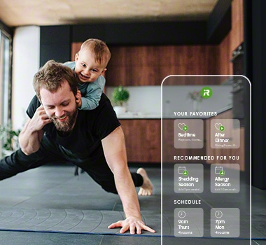 iRobot app is opened against a background of a father doing exercise with baby on his back. 